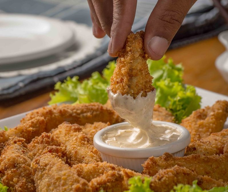 person dipping fried cuisine on dip